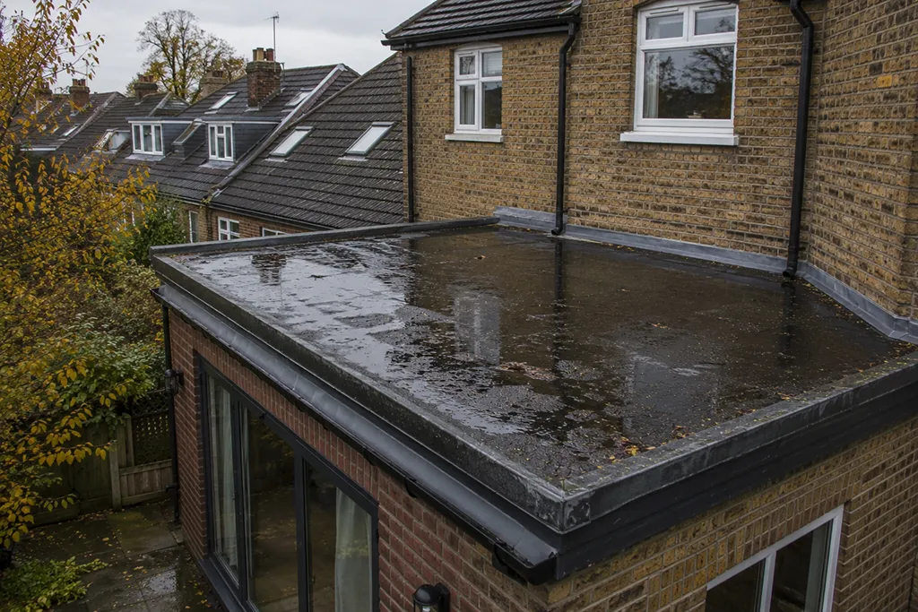 Residential property in London with flat roof holding rainwater after heavy rain