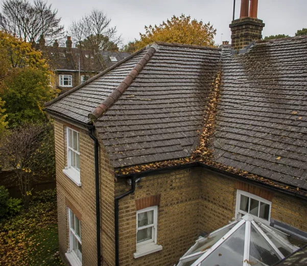 Residential roof in London with autumn debris visible in roof valley and guttering