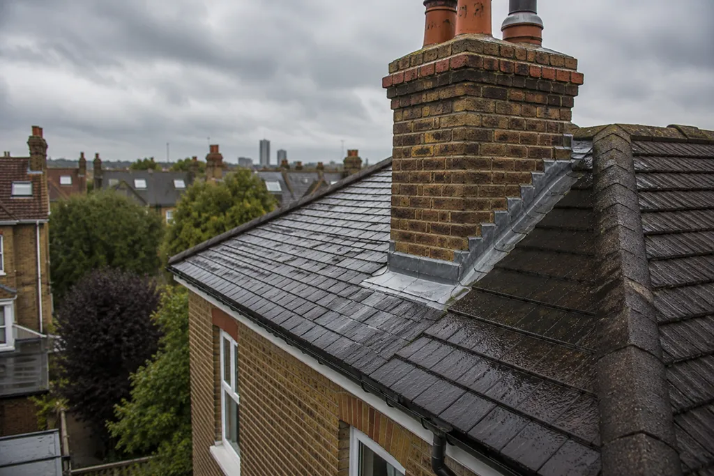 Residential roof in London with chimney and flashing visible in wet weather