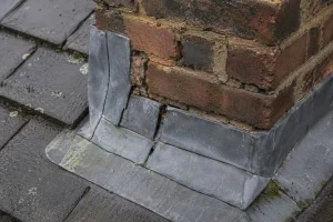 Loose chimney flashing and deteriorating mortar on a pitched roof before winter